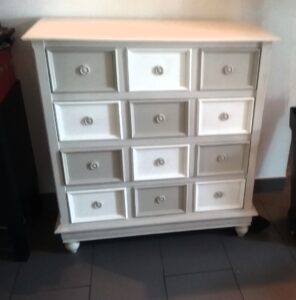 commode relooké de couleur blanche et grise composé de quatre tiroir et une plinthes sur la partie basses et des pied tourné
